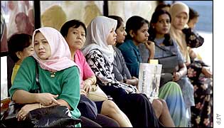 A group of women of different races wait at a bus stop in Kuala Lumpur