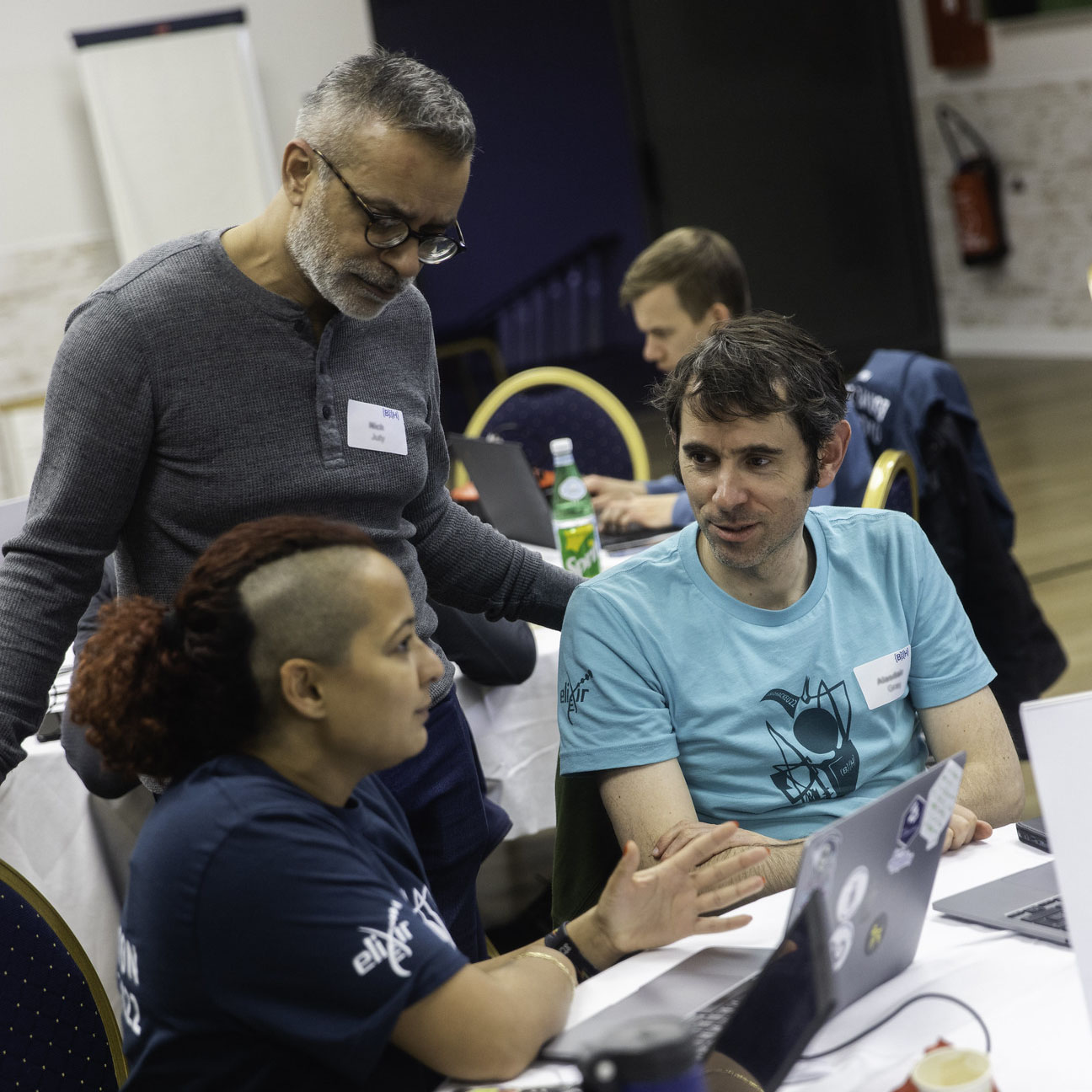 Three people chatting in front of a laptop