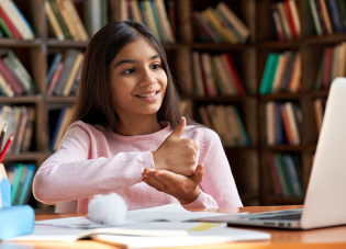 A young girl uses sign language to communicate virtually on a laptop