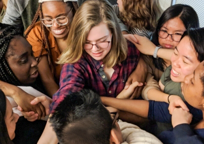 A group of GT students in a tight circle handshaking.