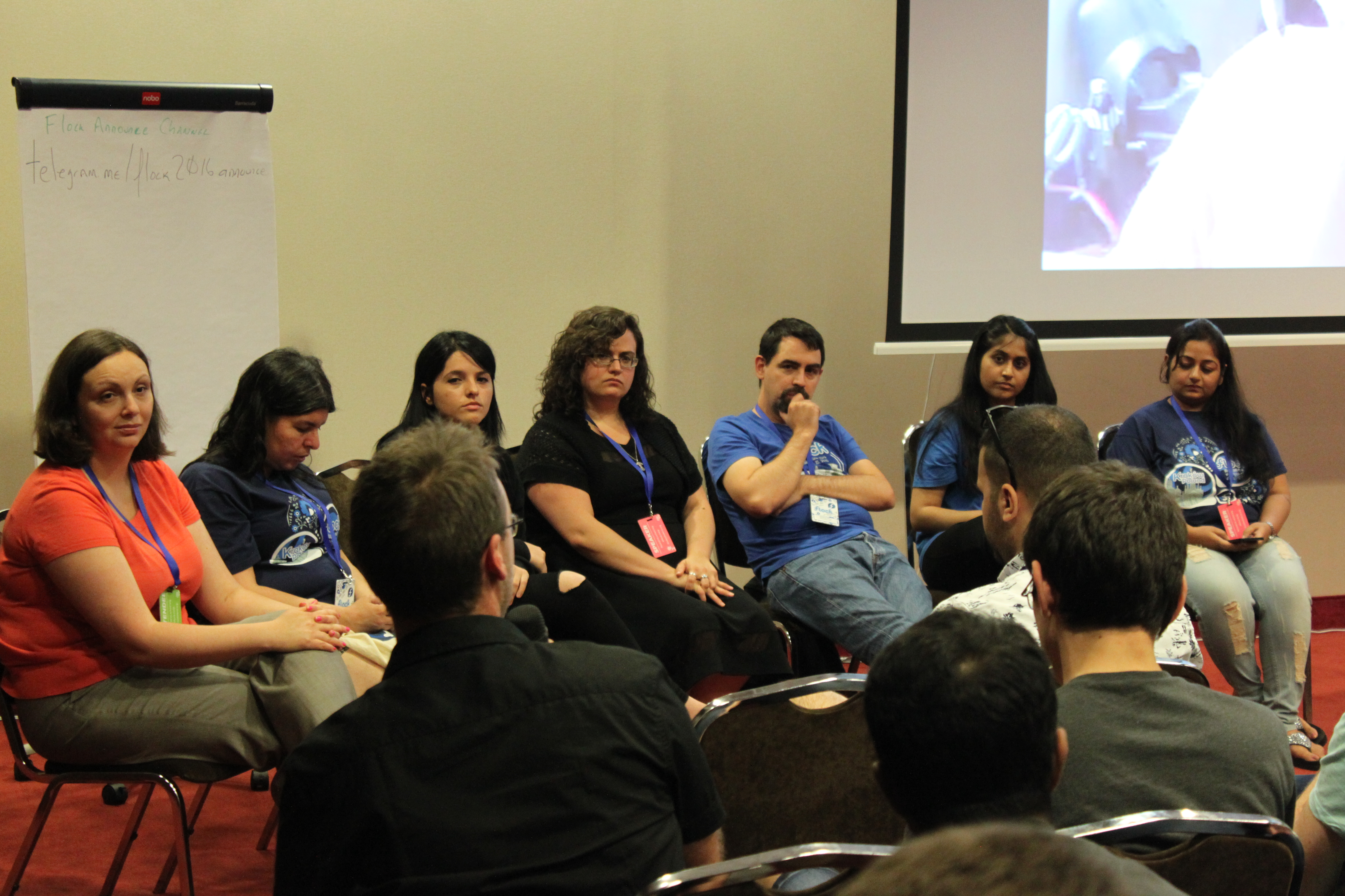 A panel of people sitting in a semicircle at the front of a room taking questions from an audience