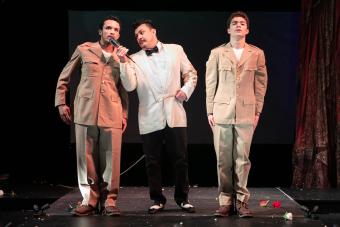 An emcee in period costume talks to an actor in a soldier's uniform