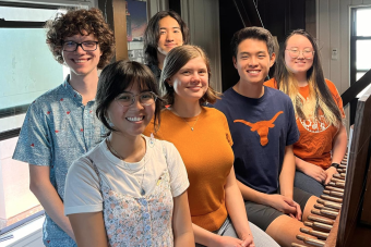 A group of five students pose with the carillon inside the UT Tower