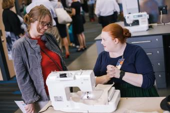 A student demonstrates how to use a sewing machine