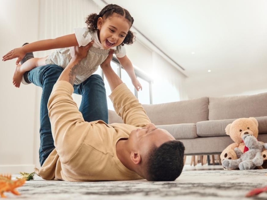 dad flying daughter on legs