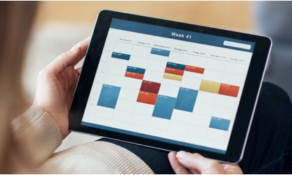 person holding tablet with calendar on screen