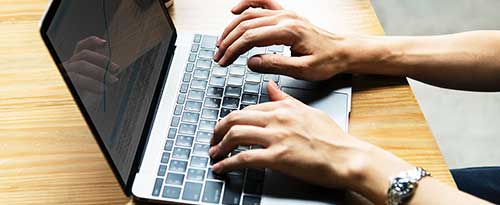 hands typing on laptop keyboard