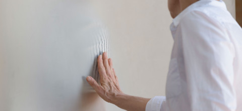 A woman touching a opaque screen with a pattern visible behind