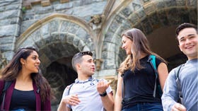 Four students joke with each other while descending the stairs at Healy Hall