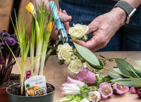 A person using trimming tools to create a floral design arrangement.