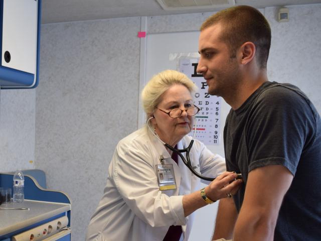 Practitioner checking patient lungs with stethoscope 