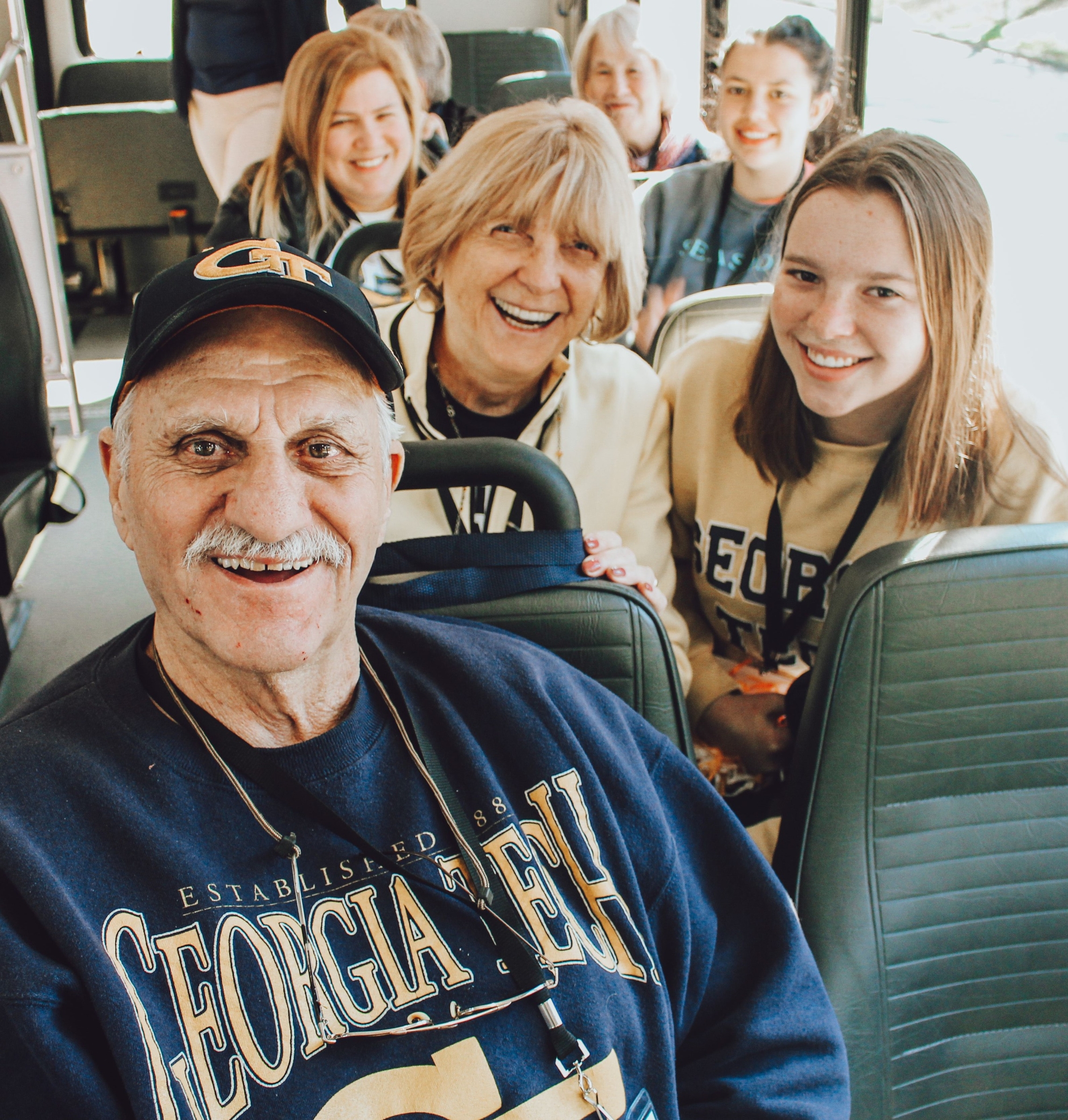 Grandparents with granddaughter riding a bus.