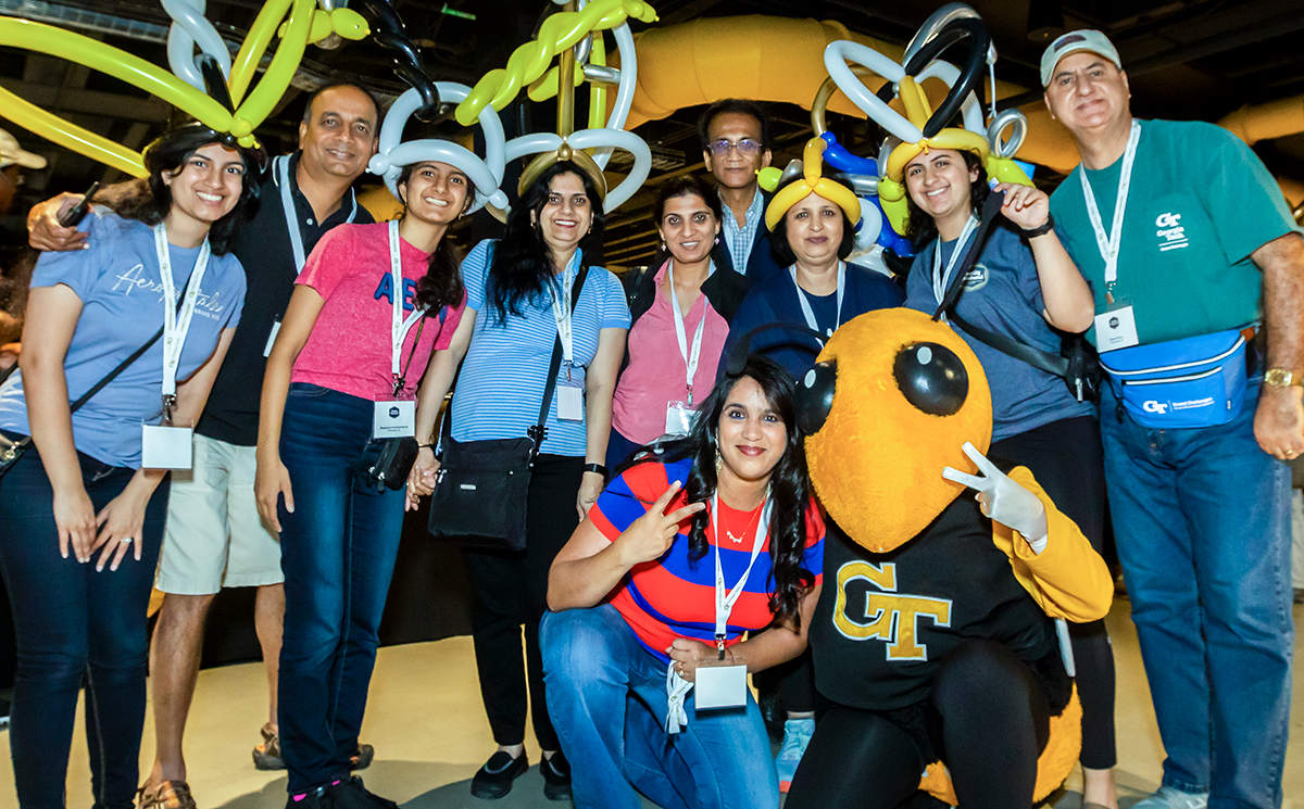 A family of 10 wearing balloon hats posing with Buzz during the 2022 Family Weekend.