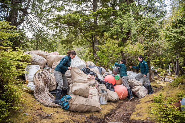 Three people in Parks Canada uniforms piling bags of trash