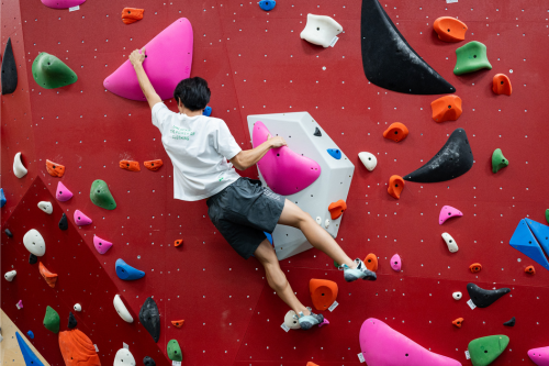 A student bouldering on one of the walls in the indoor bouldering zone facility