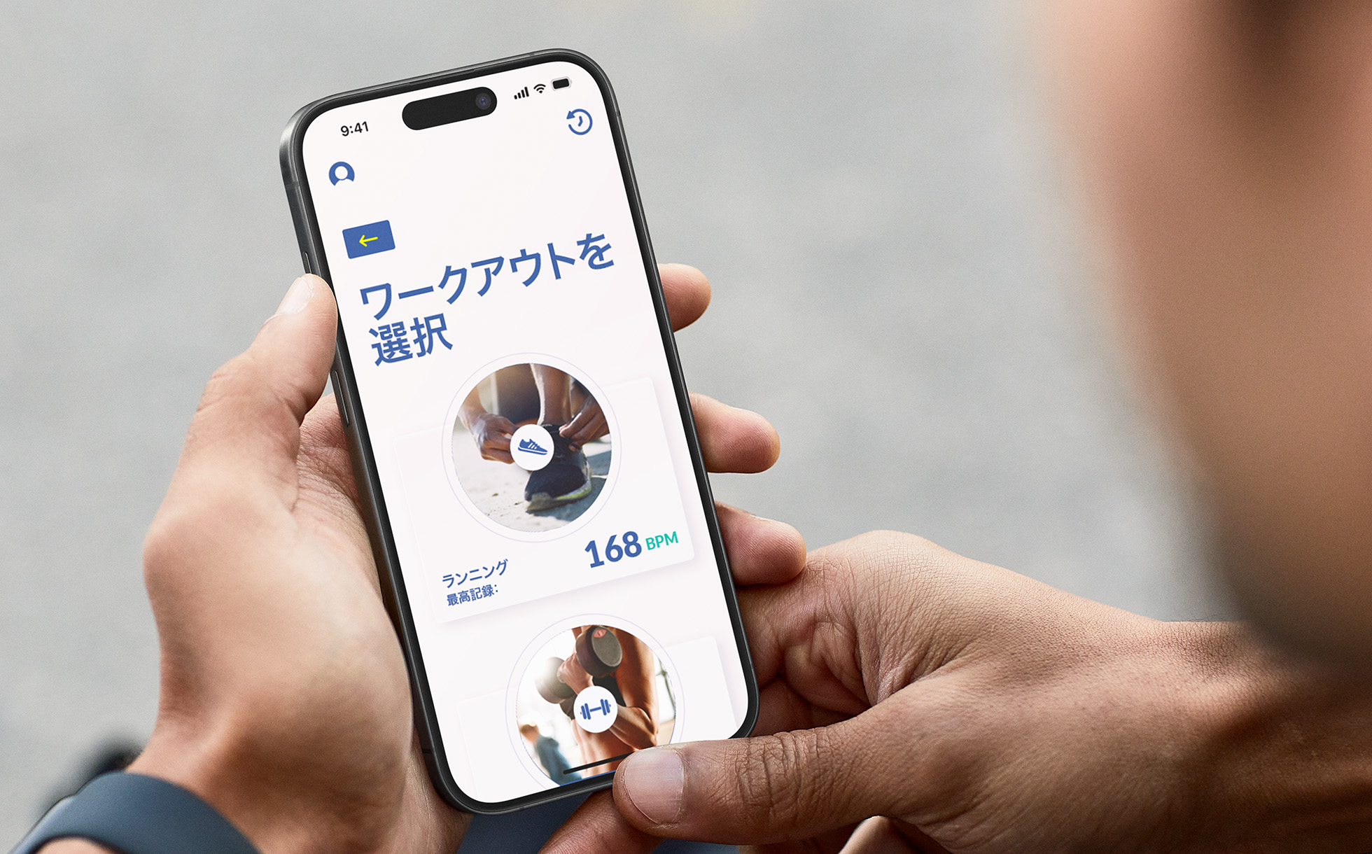 1人の人物がiPhoneでサンプルAppのSprint Pacerを使用している。画面に「Select workout」（ワークアウトを選択）オプションが表示され、過去のランニングの指標が示されている。 