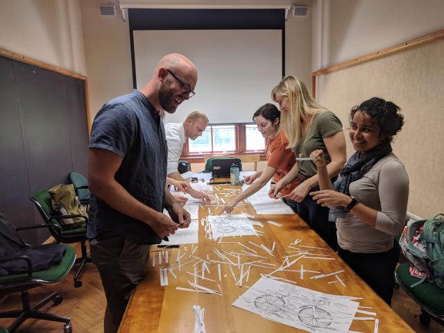 Students working together on a project with papers strewn on top of a table