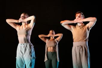 Three dancers cover their mouths 