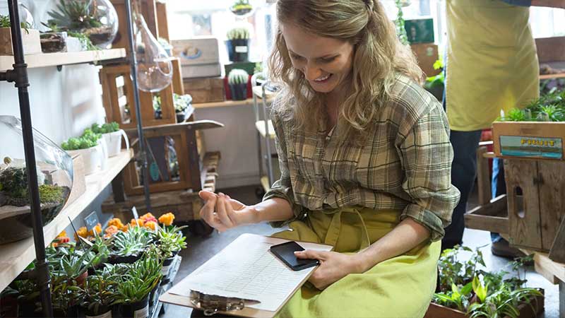 Woman looking at a list while sitting inside a flower shop.