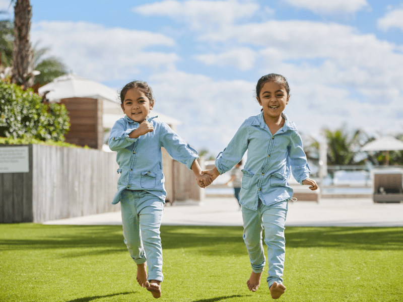 Two kids running while holding hands 