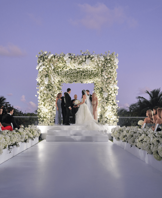 Couple in weddings dress and tux outside at a flower alter