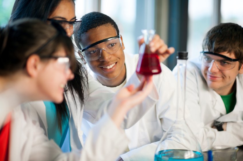 White coat students observing a beaker.