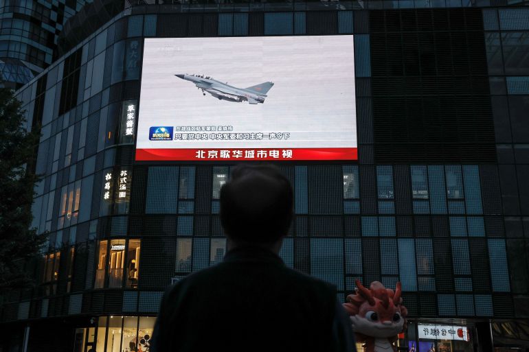 A man looks at a giant screen showing news footage of military drills conducted in areas around the island of Taiwan by the Eastern Theatre Command of the Chinese People's Liberation Army (PLA), in Beijing, China May 24, 2024. REUTERS/Tingshu Wang