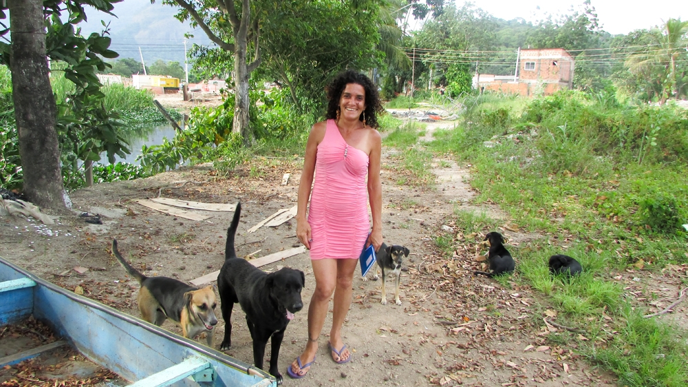 Sandra with some of the stray dogs that resettled members of the community have had to leave behind [Maya Thomas-Davis/Al Jazeera]