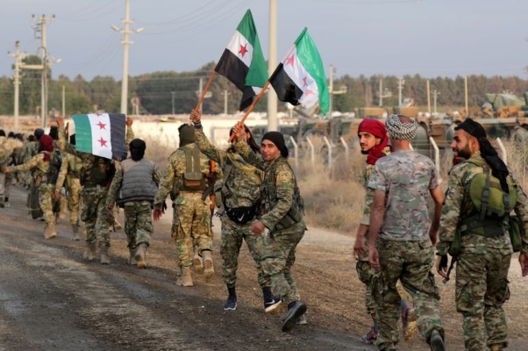 Turkey-backed Syrian rebel fighters hold the Syrian opposition flag as they walk together in the border town of Akcakale in Sanliurfa province