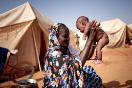 A woman plays with her baby in an IDP camp in Sevare, Mali [Michele Cattani/AFP]