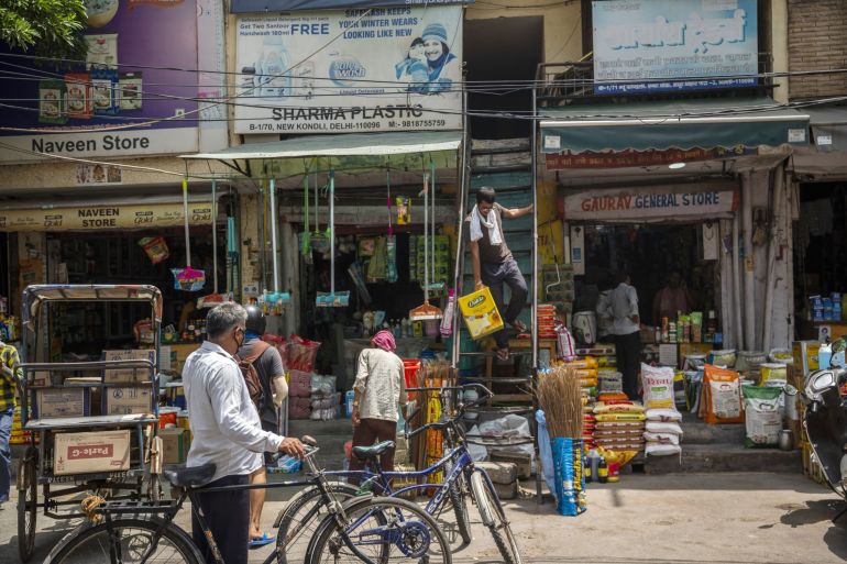 A man carries a box of sunflower oil down a store's flight of stairs at the Kondli Wholesale Market in Noida, India