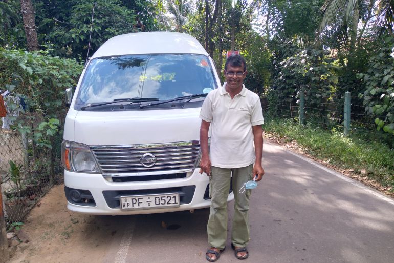 A man stands in front of a vehicle