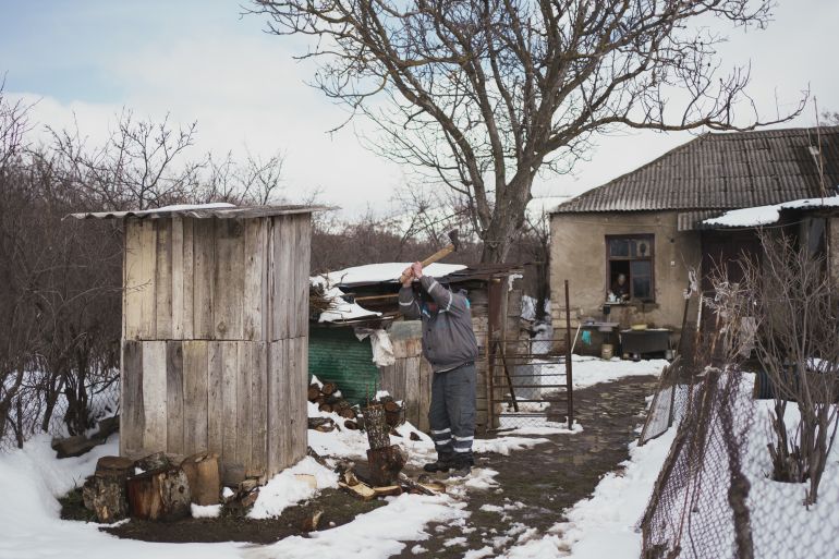 A photo of a person chopping wood outdoors in the snow.