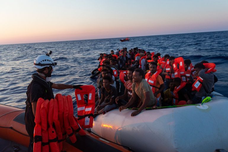 Crew of the Sea-Watch 3 distribute life jackets to 108 people in a boat in distress in the central Mediterranean