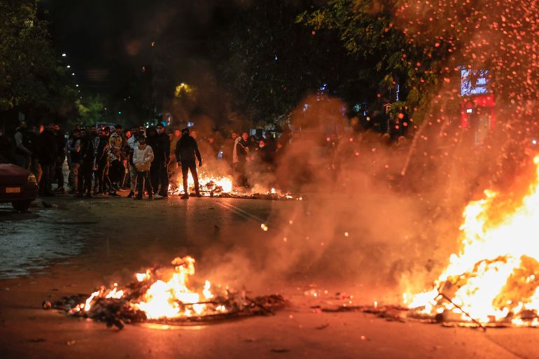 People blocking a main road set fire to rubbish bins outside the Ippokrateio General Hospital, in Greece's second largest city of Thessaloniki, on Monday, Dec 5, 2022. Dozens of Roma men protested Monday outside a hospital in northern Greece where a Roma teenager was being treated in critical condition, having been shot by police in a road chase after he allegedly drove off from a gas station without paying. (AP Photo/Dimitris Tosidis)