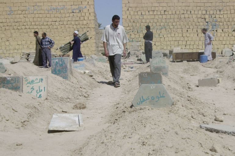 Iraqis walk through a soccer field turned into a cemetery, in Fallujah, Iraq, Sunday, April 11, 2004. More than 600 Iraqis have been killed in the fighting in Fallujah the past week, the head of the city's hospital said Sunday. (AP Photo/Abdel Kader Saadi)