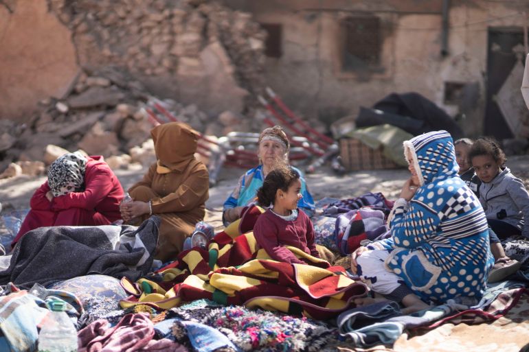 CORRECTS NAME OF VILLAGE Families sit outside their destroyed homes after an earthquake in Moulay Brahim village, near Marrakech, Morocco, Saturday, Sept. 9, 2023. A rare, powerful earthquake struck Morocco late Friday night, killing more than 800 people and damaging buildings from villages in the Atlas Mountains to the historic city of Marrakech. But the full toll was not known as rescuers struggled to get through boulder-strewn roads to the remote mountain villages hit hardest. (AP Photo/Mosa'ab Elshamy)