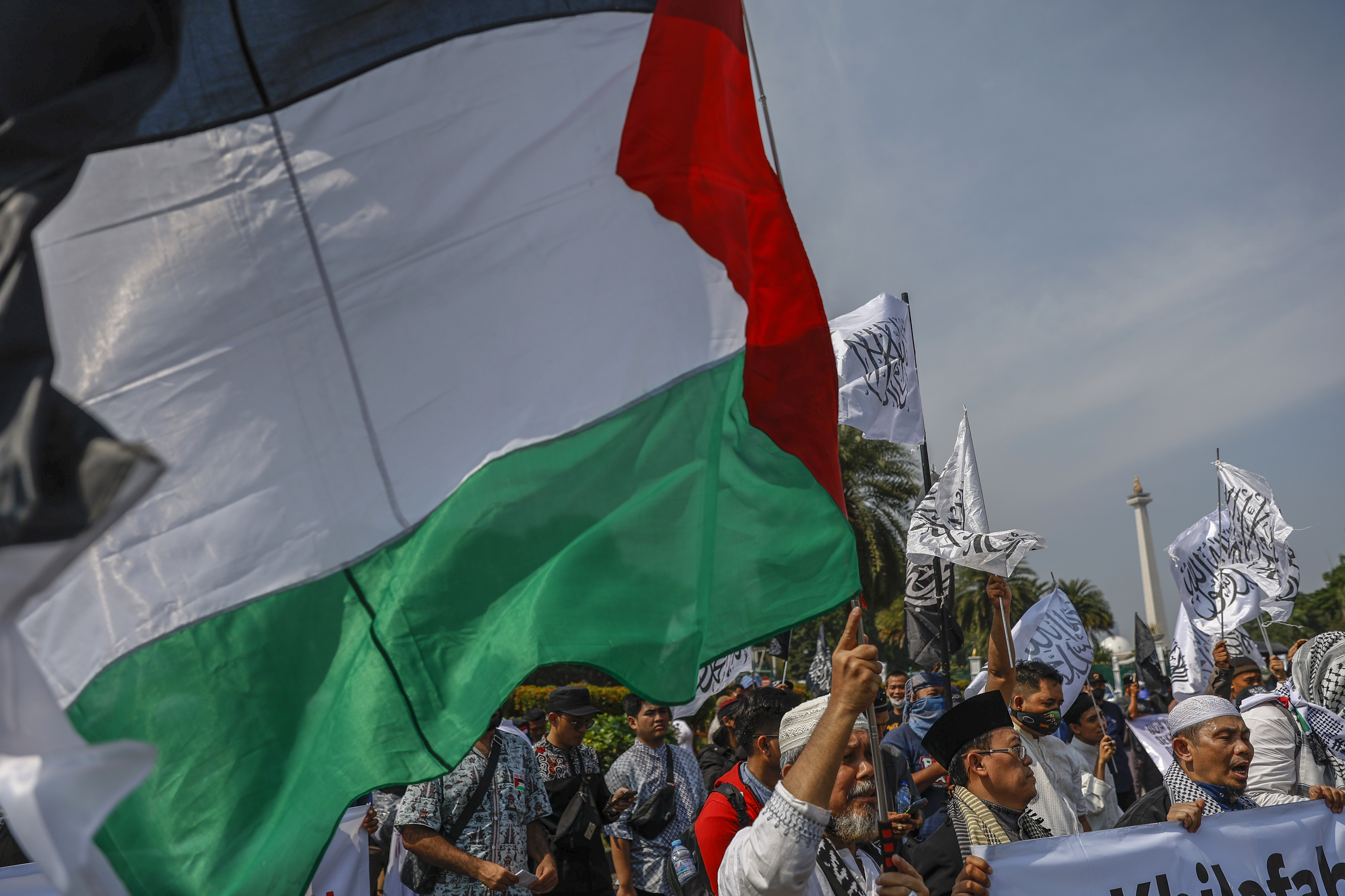 Muslims hold a Palestinian flag and banners as they shout slogans during a rally supporting the Palestinians, in Jakarta