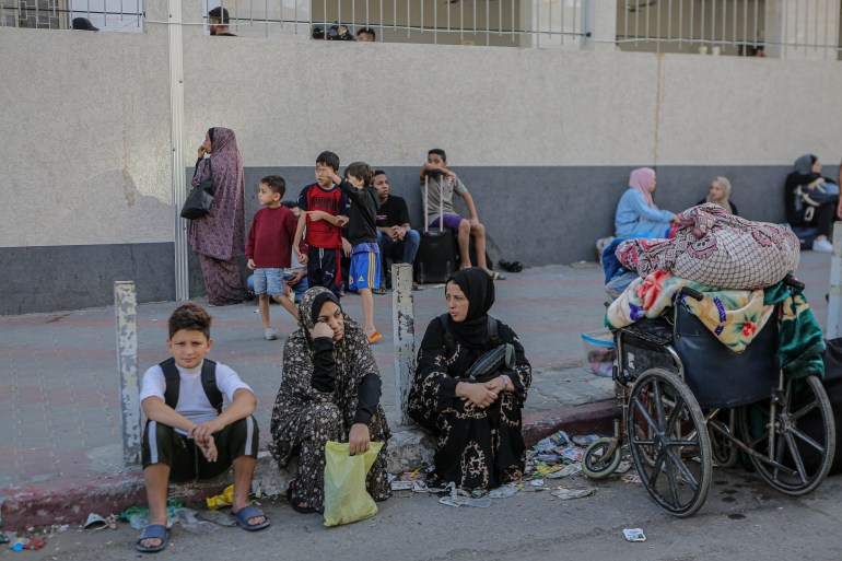 Palestinian women sit on the pavement with barely any belongings