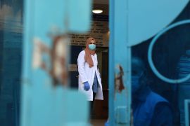 Palestinian UN doctor mask-clad due to the Covid-19 coronavirus stands behind a door at a clinic in Bureij refugee camp central of Gaza Strip