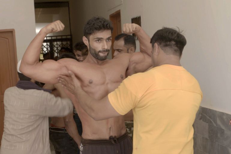 A bodybuilders getting tanning gel applied on his muscles on competition day