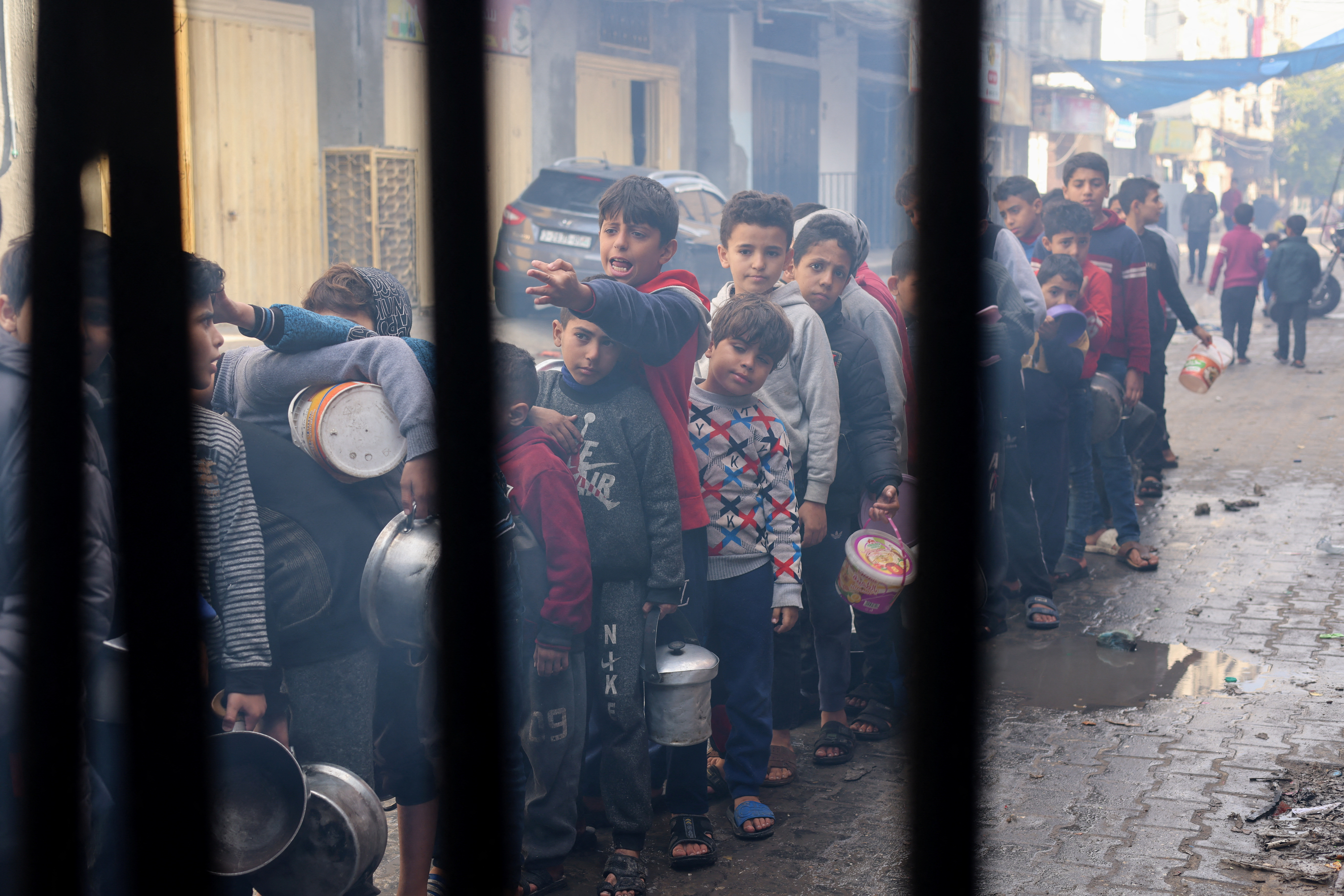 Palestinian children queue to receive food cooked by a charity kitchen, amid shortages in food supplies, as the conflict between Israel and Hamas continues, in Rafah in the southern Gaza Strip.