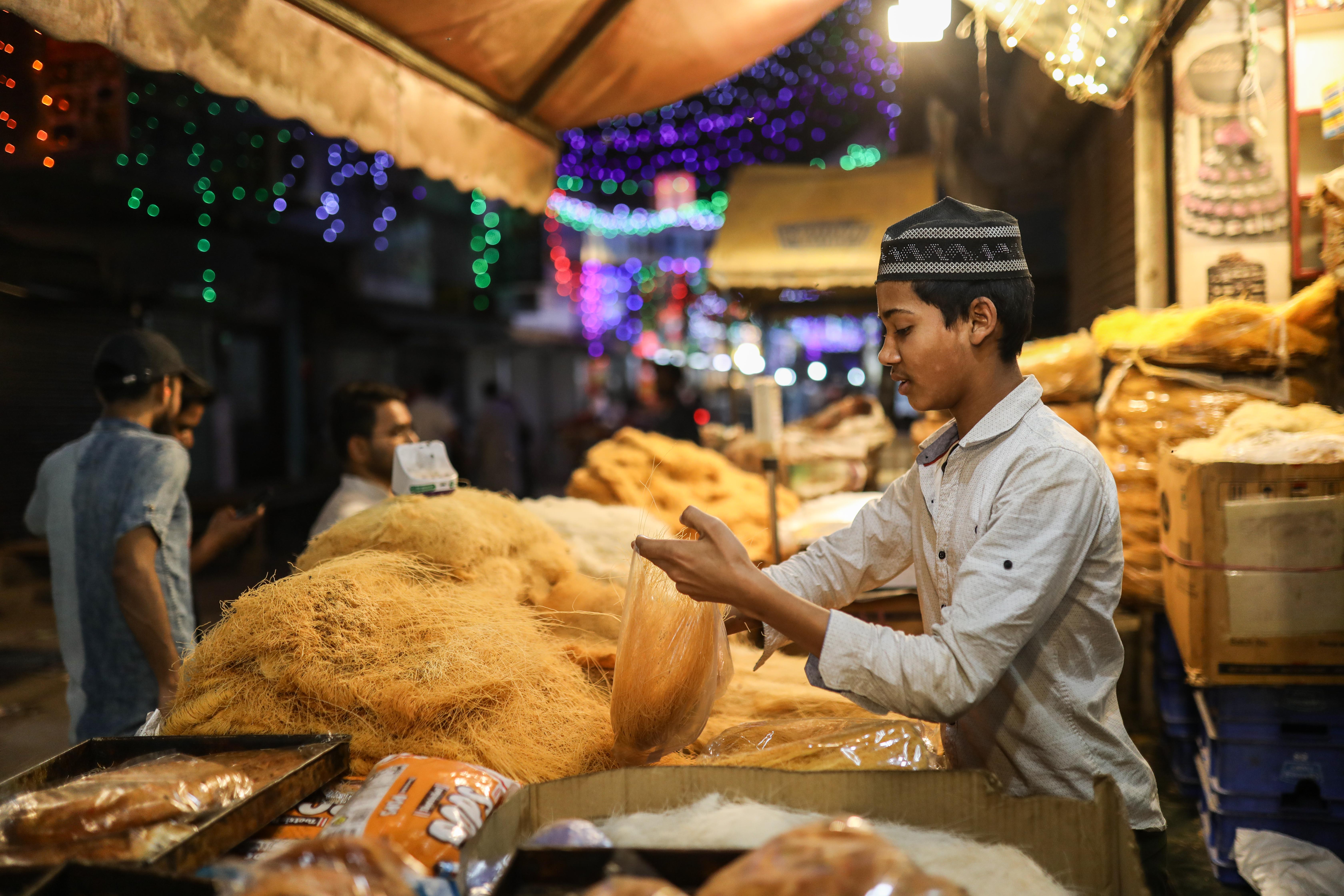 A boy sells dry rice vermicelli at a food stall in Shaheen Bagh. [Meer Faisal/Al Jazeera]