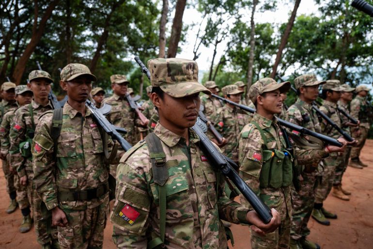 This photo taken on December 8, 2023 shows members of the Mandalay Peoples Defense Forces (MDY-PDF) taking part in a flag raising ceremony at their base camp in the forest near Namhsan Township in Myanmars northern Shan State. - A squad of Myanmar pro-democracy fighters works quickly to ready drones for an attack on a nearby military base, the latest target in a wave of aerial assaults that has helped turn the war against the junta. (Photo by AFP) / TO GO WITH MYANMAR-COUP, FOCUS - TO GO WITH Myanmar-coup, FOCUS