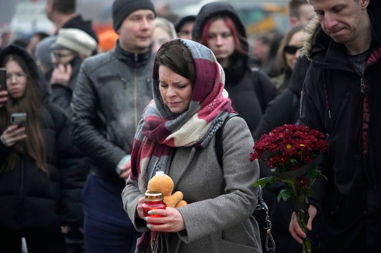 People place flowers and toys by the fence next to the Crocus City Hall, on the western edge of Moscow, Russia, Saturday, March 23