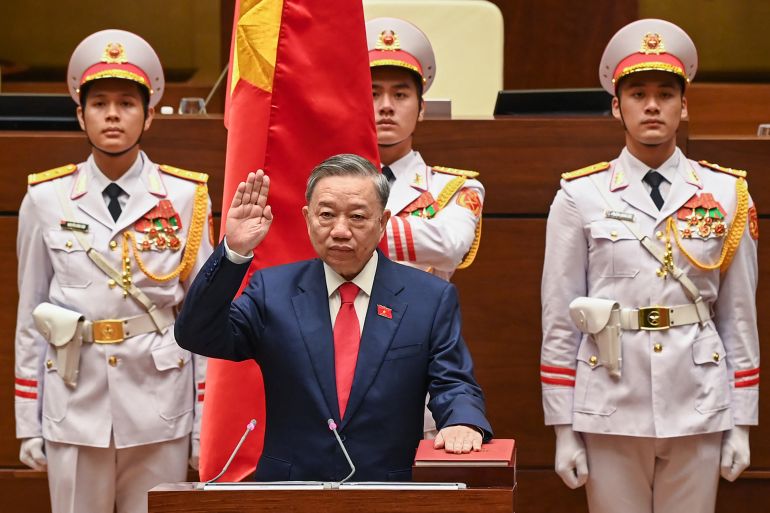 To Lam takes the oath as Vietnam's new president. He has his left hand on a red book and his right raised. There are three men in white ceremonial uniforms behind him