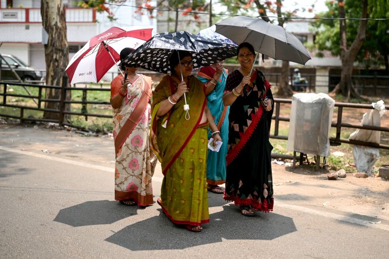 Women carrying umbrellas arrive to cast their ballots to vote at a polling station in Dhanbad, in India's Jharkhand