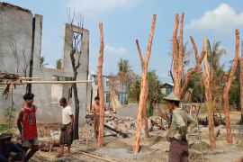 People rebuilding their homes after they were destroyed in fighting between the military and Arakha Army. There are lots of damaged trees.