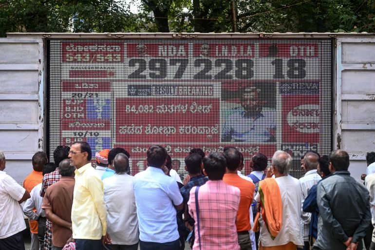 People watch latest vote counting results live on a large screen for India's general election at the Bharatiya Janata Party (BJP) office in Bengaluru