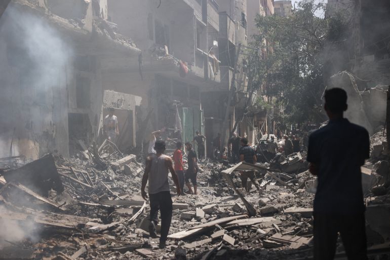 Palestinians walk on the rubble of destroyed buildings following an assault by the Israeli army in the Nuseirat camp, in the central Gaza Strip on June 8, 2024